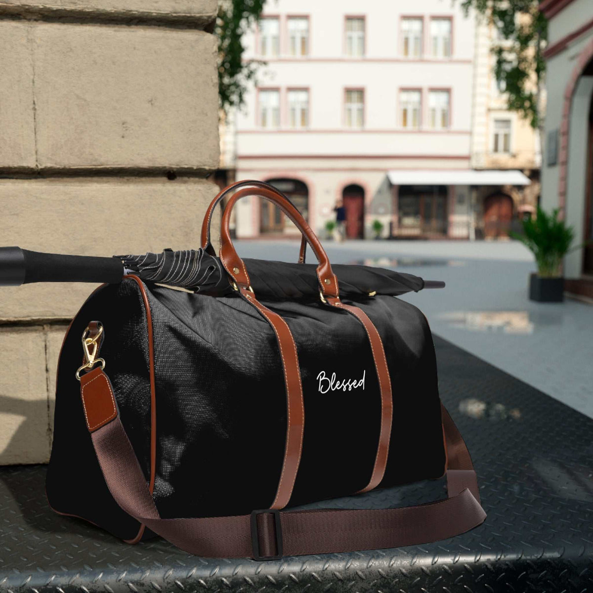 Black Blessed travel bag with brown PU leather handles, adjustable shoulder strap, gold zipper, and durable nylon material for versatile use