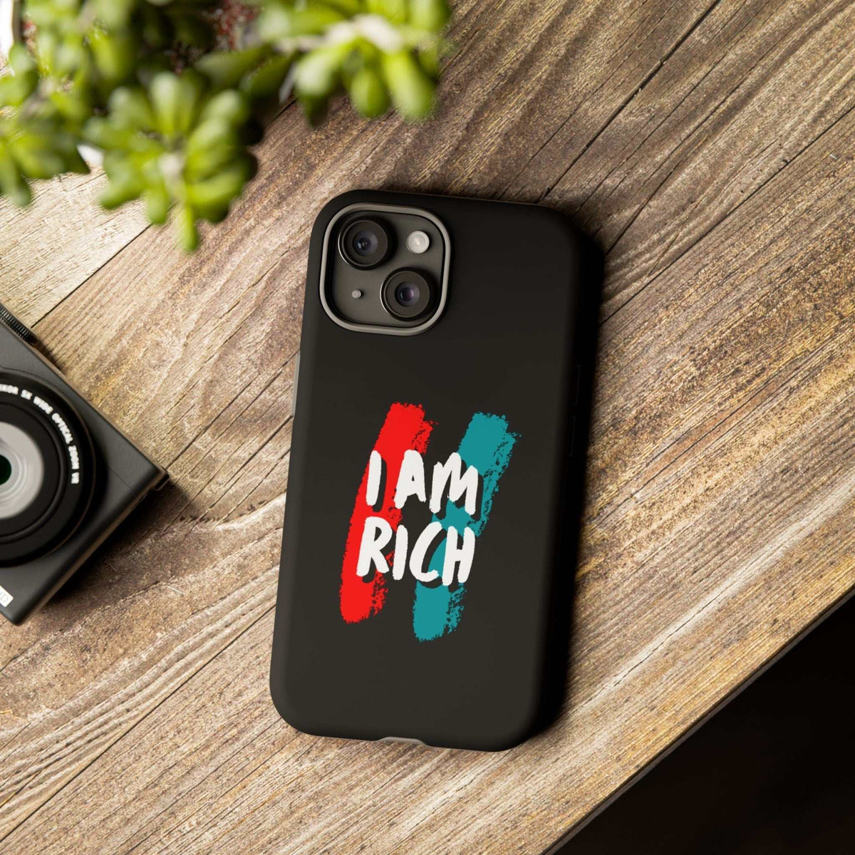 Black I Am Rich phone case with matte finish and bold text design on wooden surface