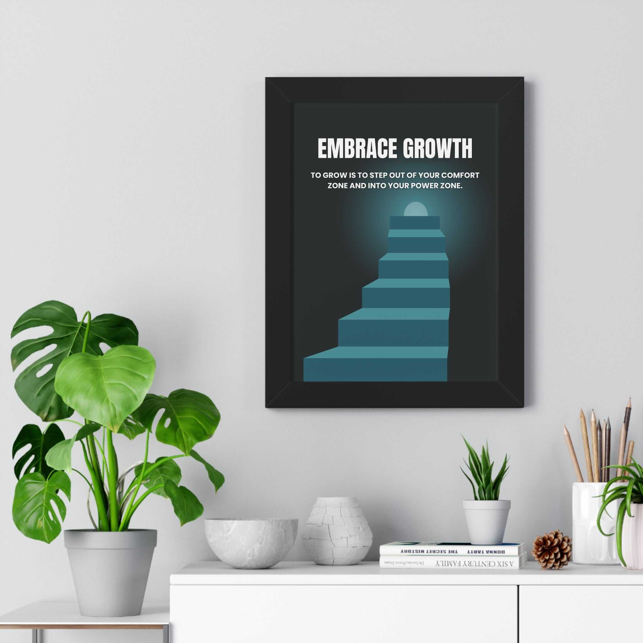 Embrace Growth motivational poster with staircase design in black frame on wall above white shelf with plants and books
