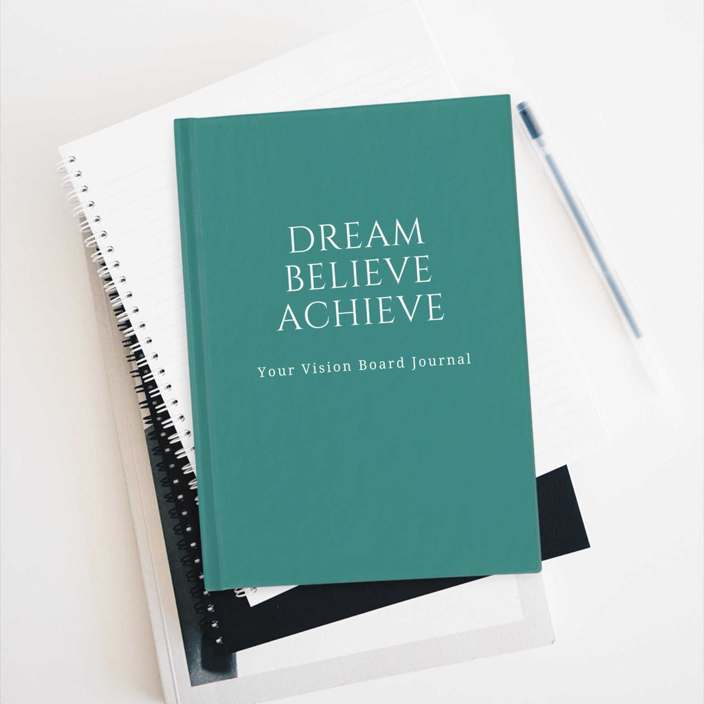 Green Vision Board Journal with "Dream Believe Achieve" cover text on top of notebooks and pen