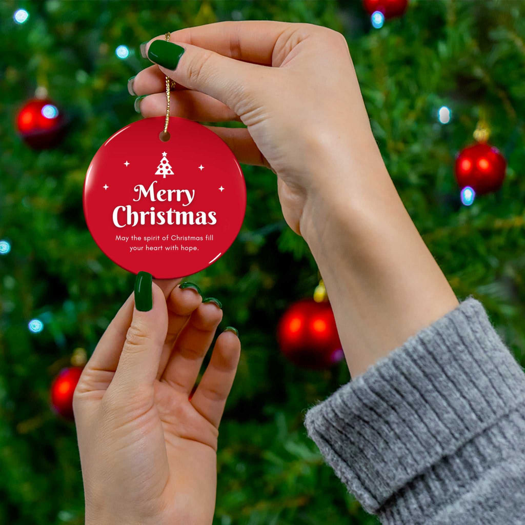 Hand holding red round Christmas Hope Ornament with gold string