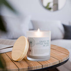 Lit glass candle with frosted vessel and maple lid on wooden table