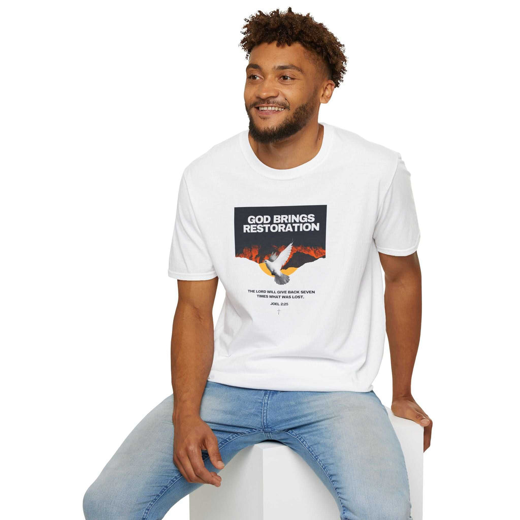 Man wearing white Restored by Grace T-shirt with faith message and jeans sitting on white cube
