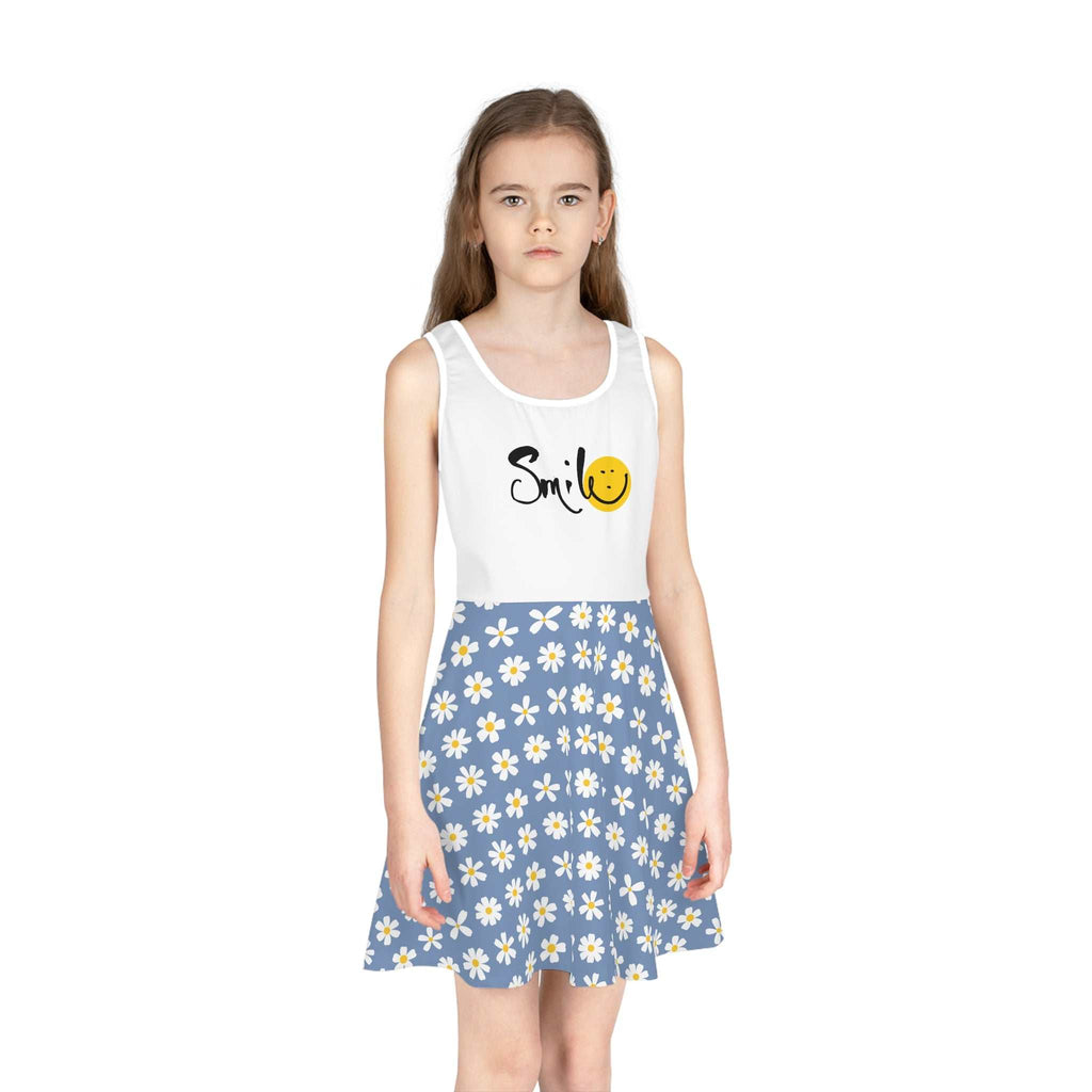 Girl wearing a mid-length sleeveless sundress with a white top featuring "Smile" and a smiley face, and a blue A-line skirt with white daisies.